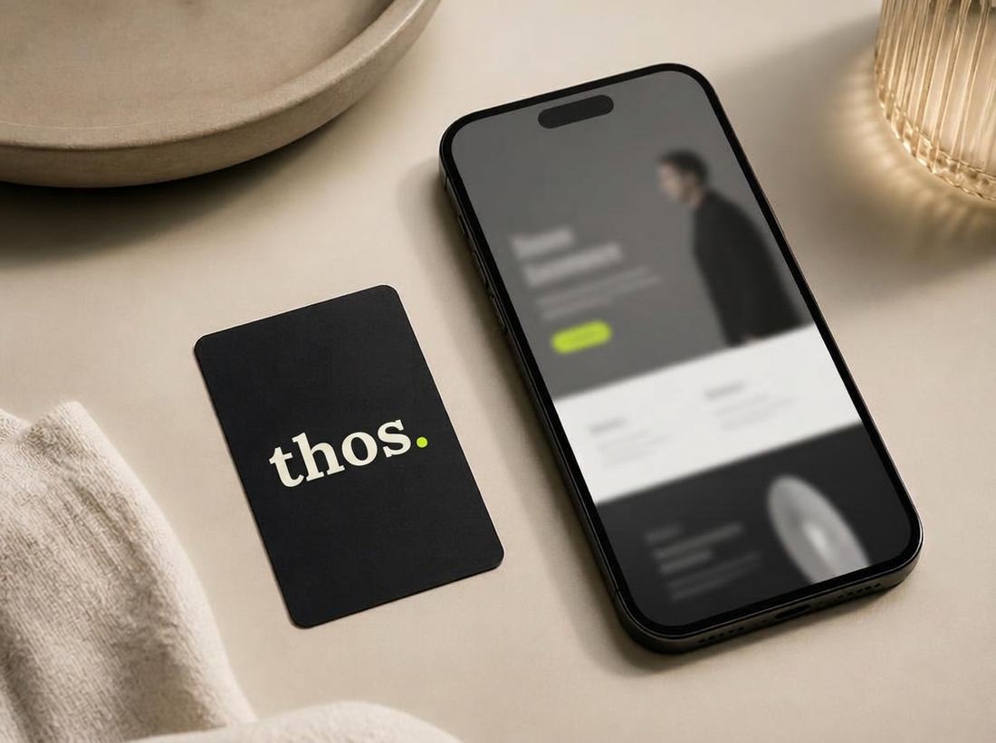 Matte black NFC business card beside a phone showing a clean one-page website.